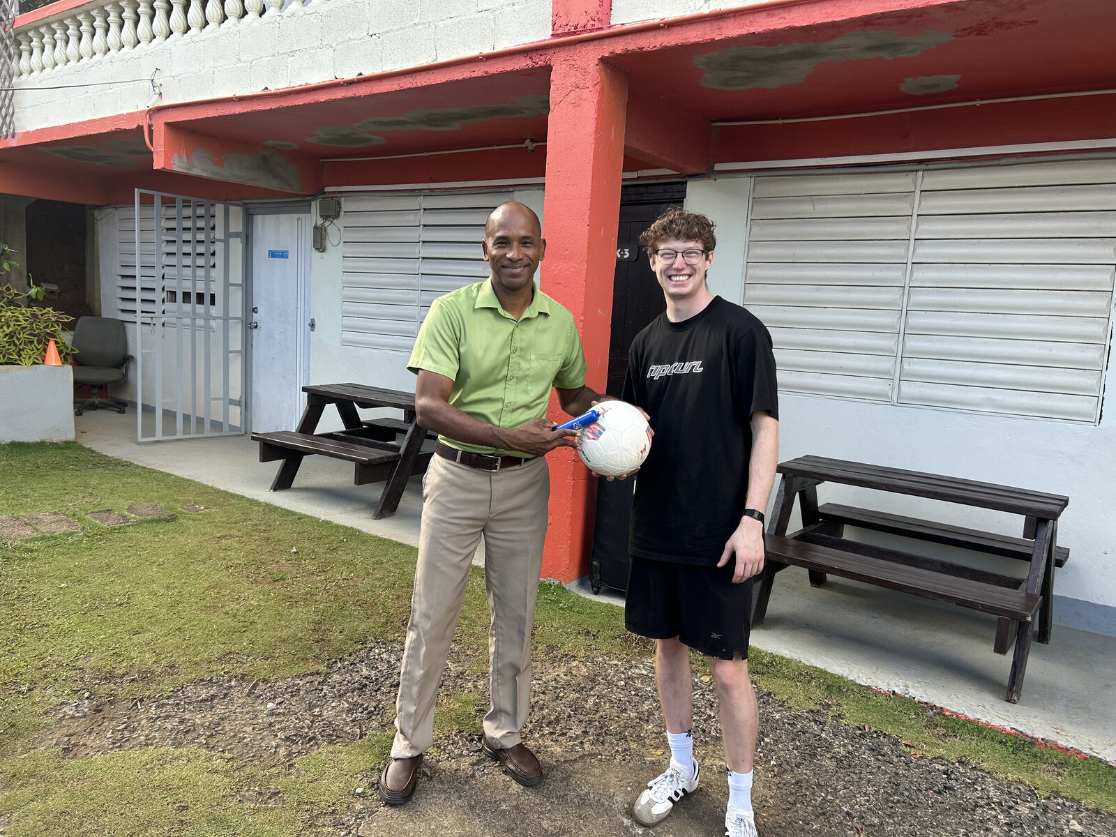 Handing off donated soccer gear with a Kalinago community leader, January 2026
